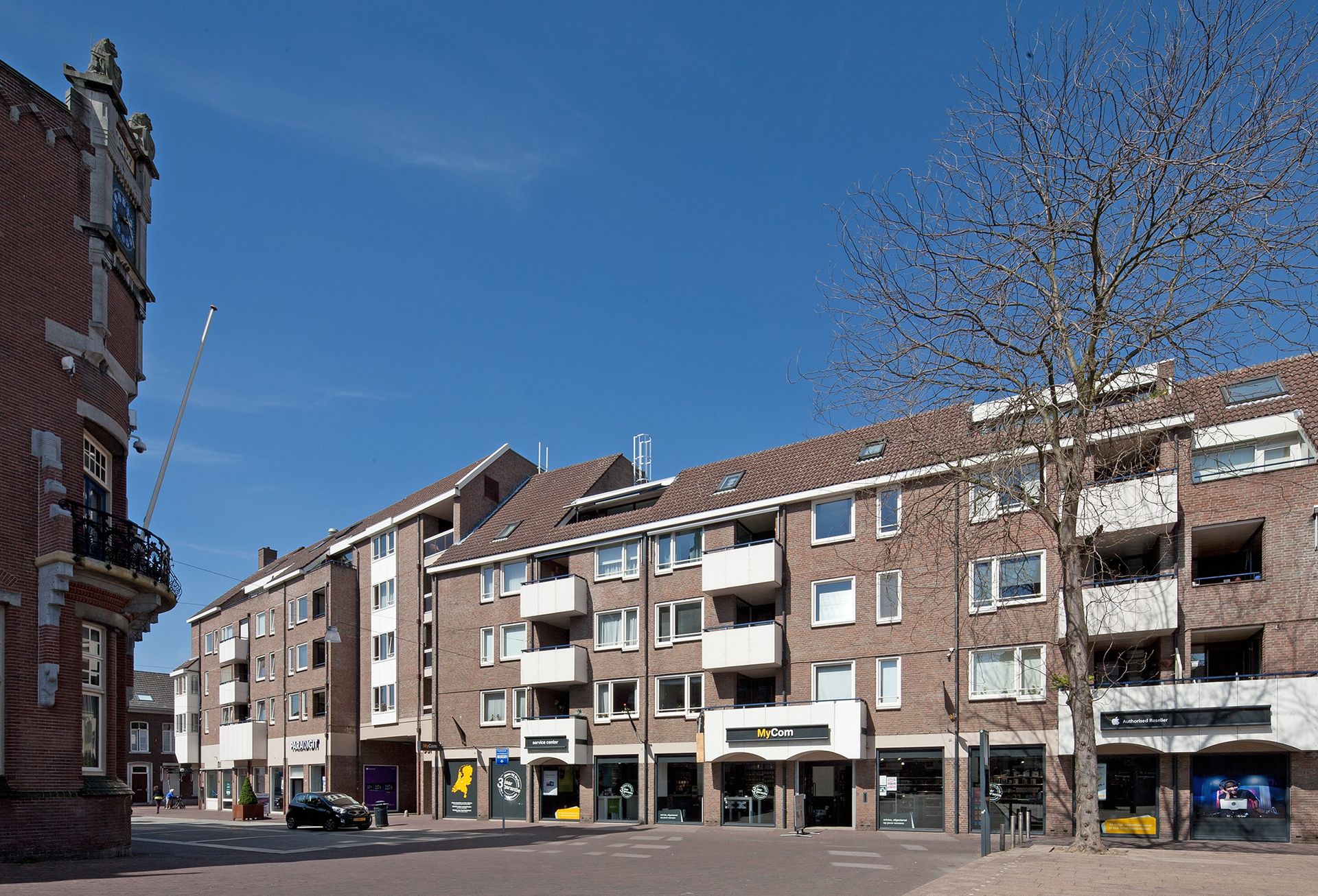 Vooraanzicht van een appartementencomplex en winkels tegenover Theaterhotel De Oranjerie in Roermond